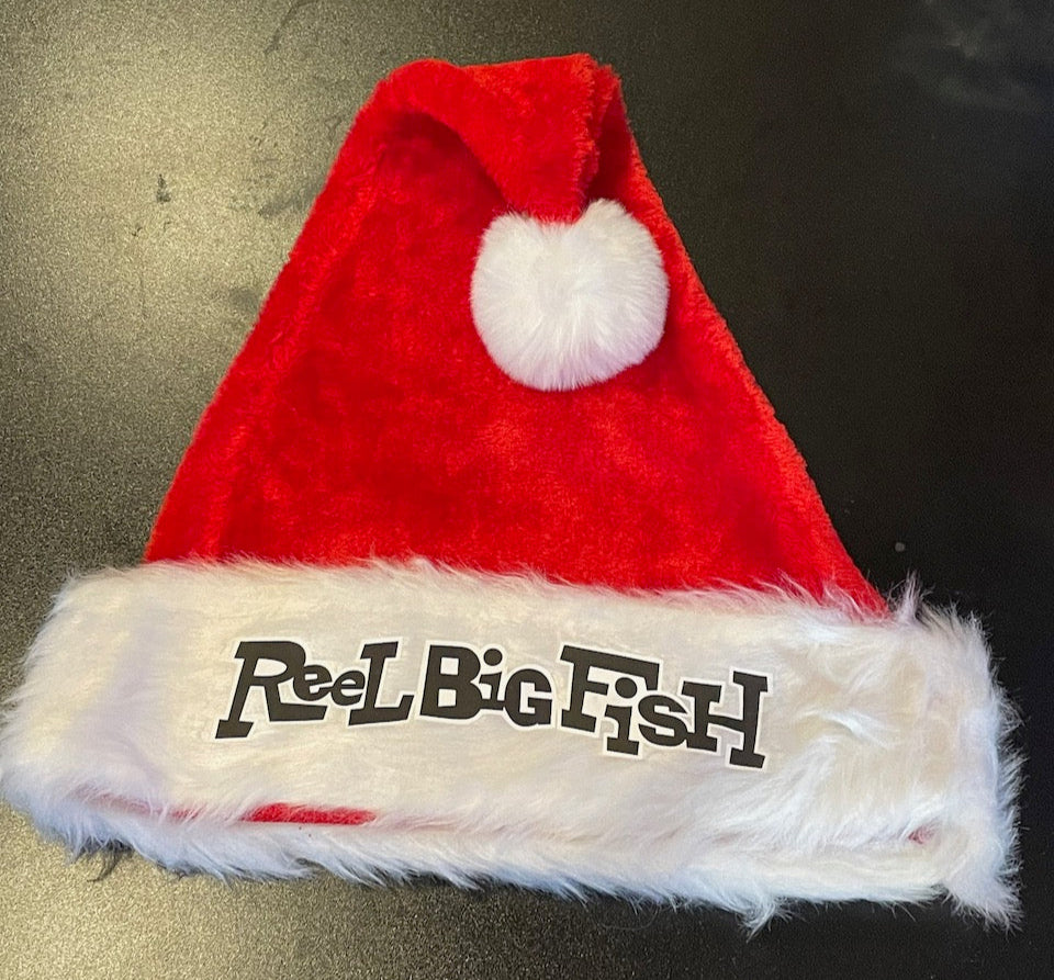 Red Santa hat with white fur trim and 'Reel Big Fish' text on a dark surface
